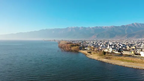 Aerial view of wide lake surface lakeside tidal flat town in Dali Yunnan China Video stock 337922020