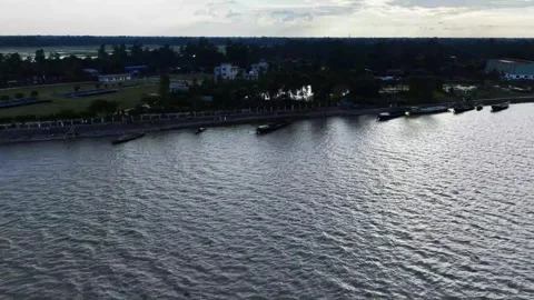 Aerial view of a wide rippling river beside a tree-lined waterfront with sm.. 库存影片 344054271