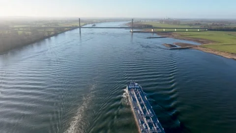Aerial view of a wide river with two cargo ships leaving long wakes Видео 329077220
