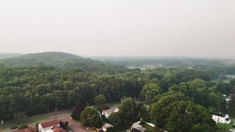 Aerial view of wildfire smoke spreading over a suburban forest... Видео 340291078