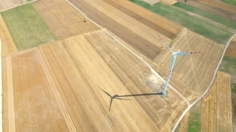Aerial view of wind turbine casting shadow on harvested agricultural fields in Stock Footage 287492539