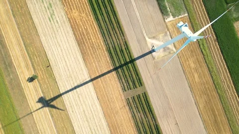 Aerial view of a wind turbine casting a shadow over colorful farmland in the Stock Footage 287497544