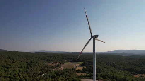 Aerial view of a wind turbine generating renewable energy over a green forest Stock Footage 344680450