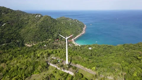 Aerial view of the wind turbine surrounded by greenery and sea. Stock Footage 166673746