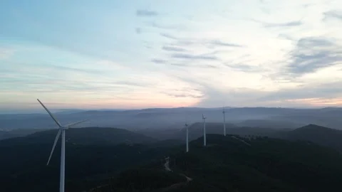 Aerial view of wind turbines generating renewable energy on a mountain at sunset Stock Footage 327275734