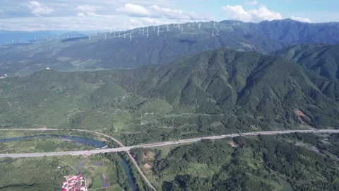 Aerial View of Wind Turbines on Mountain Ridges Above Highway and River Valley Stock Footage 342017824
