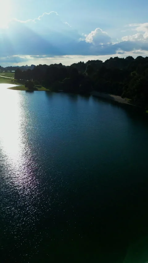 Aerial view of a winding lakeshore path beside turquoise water with algae Stock Footage 346014735