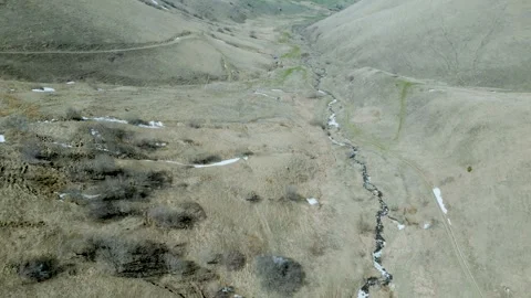 Aerial view of winding mountain river valley. Snow thawed along the banks, trees Stock Footage 257424768
