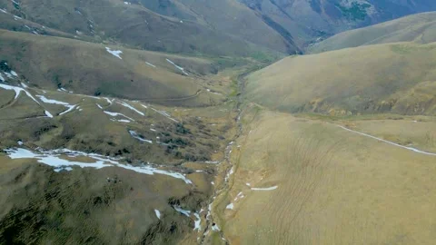 Aerial view of winding mountain river valley. Snow thawed along the banks, trees Stock Footage 257459513