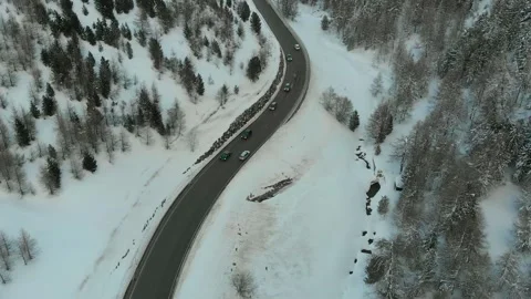 Aerial view of winding mountain road through snowy forest Stock Footage 341607940