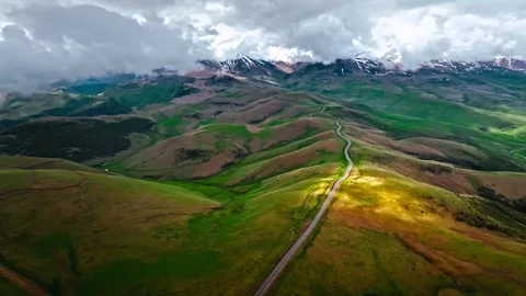 Aerial view of winding mountain road cutting through rolling green hills Stock Footage 343695682