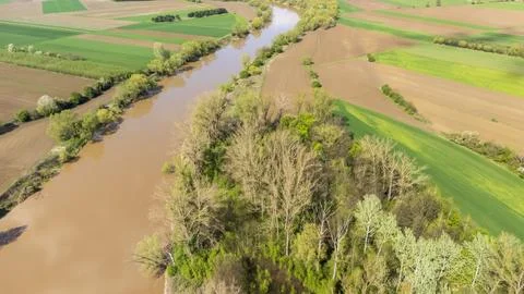 Aerial view of a winding river bordered by lush greenery and patchwork farmland Stock Photos