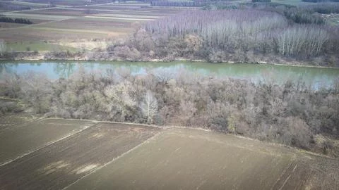 Aerial view of a winding river bordered by dense trees and agricultural fields Stock Photos