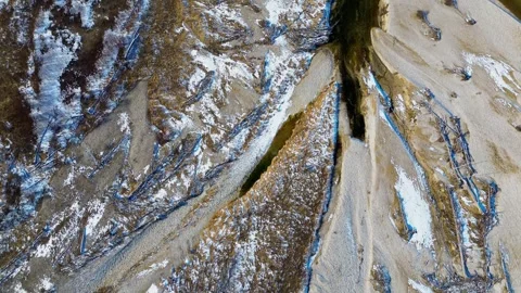 Aerial view of a winding river cutting through a rugged winter landscape, with Stock Footage 305032394