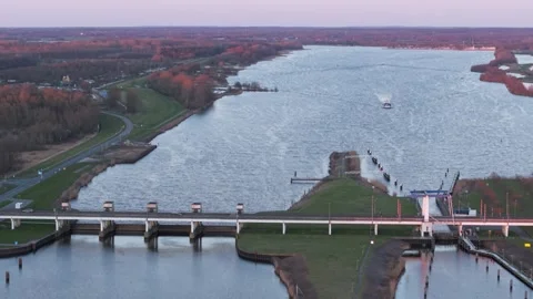 Aerial view of a winding river, a dam, and a bridge at sunset Stock Footage 321479807