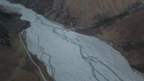 Aerial view of winding river flowing through rocky landscape, camera pans Stock Footage 320394943