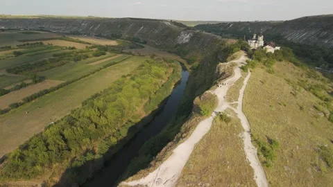 Aerial view of a winding river flowing through lush green hills and fields, with Vídeo Stock 332724897