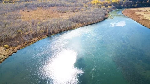 Aerial view of a winding river flowing through an autumn forest landscape Stock Footage 342325980
