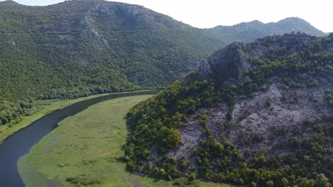 Aerial view of winding river flowing through mountainous forest valley Video stock 342771688