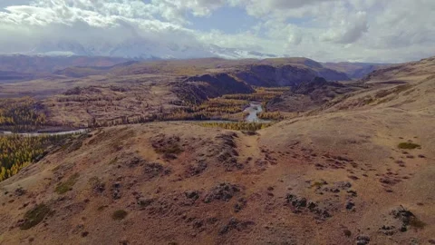 Aerial view of winding river flowing across golden autumn valley surrounded Stock Footage 343696229