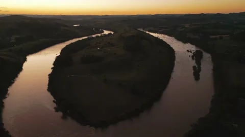 Aerial view of winding river at sunset amid green fields and forest. Stock Footage 233219784