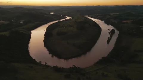 Aerial view of winding river at sunset amid green fields and forest. Stock Footage 233219797