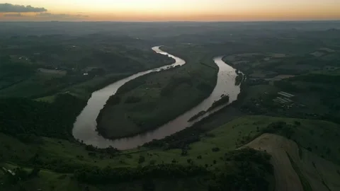 Aerial view of winding river at sunset amid green fields and forest. Stock Footage 233219816