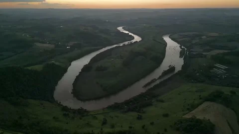 Aerial view of winding river at sunset amid green fields and forest. Stock Footage 233219817