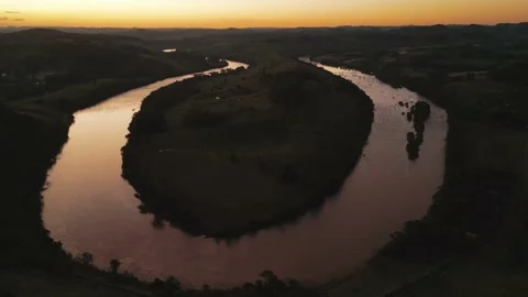 Aerial view of winding river at sunset amid green fields and forest. Stock Footage 233219818