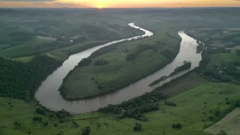 Aerial view of winding river at sunset amid green fields and forest. Stock Footage 233219824