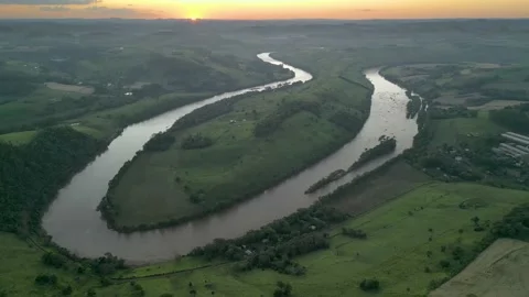 Aerial view of winding river at sunset amid green fields and forest. Stock Footage 233219835