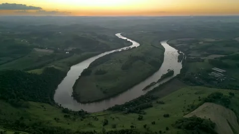 Aerial view of winding river at sunset amid green fields and forest. Stock Footage 233219845