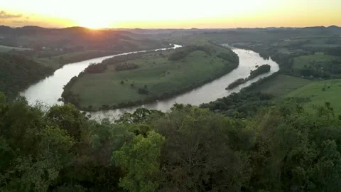 Aerial view of winding river at sunset amid green fields and forest. Stock Footage 233219854