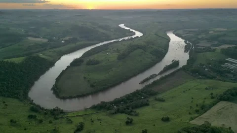Aerial view of winding river at sunset amid green fields and forest. Stock Footage 233219874