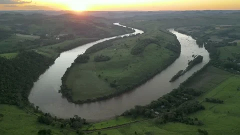 Aerial view of winding river at sunset amid green fields and forest. Stock Footage 233219886