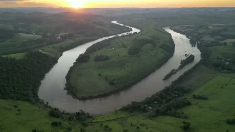 Aerial view of winding river at sunset amid green fields. Volta do Dedo Video stock 233219897