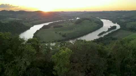Aerial view of winding river at sunset amid green fields and forest. Stock Footage 233219907