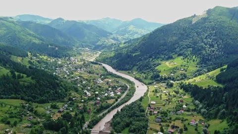 Aerial view of winding river through forested Carpathian with village, Ukraine Stock Footage 329103766