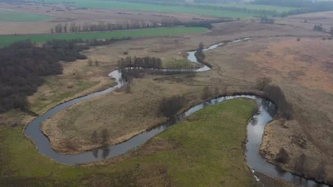 Aerial view of winding river through brown spring field Stock Footage 333833216