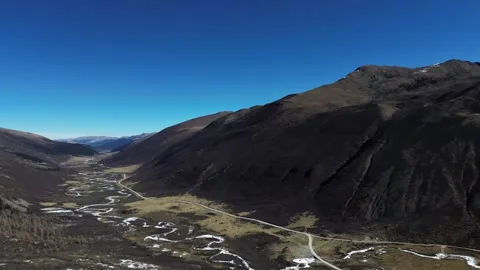 Aerial View of a Winding River Through a Mountain Valley with Snow Peaks China Stock Footage 346585927