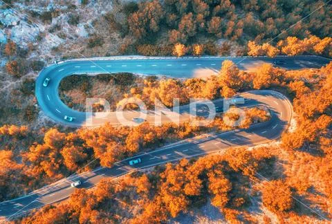 Aerial view of winding road in autumn forest at sunset Stock Photos