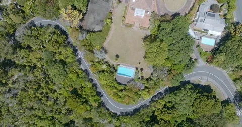 Aerial view of winding road, pool, and houses. ST HELIERS, AUCKLAND, NEW ZEALAND Stock Footage 303214087