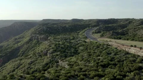 Aerial View of Winding Road Through Green Hilly Landscape Stock Footage 310649908