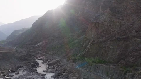 Aerial view of a winding road through a rocky riverbed in the mountains of 스톡 동영상 314455441