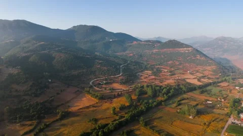 Aerial view of winding road through rural valley and mountains at sunset Stock-Footage 332253447