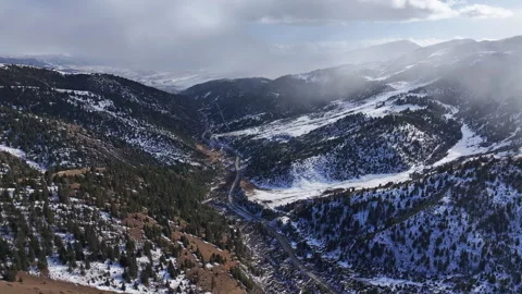 Aerial view of a winding road through snowy forests and canyons Stock Footage 332556673