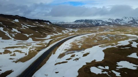 Aerial view of a winding road through snowy mountains and fields in Iceland Stockbeeldmateriaal 333916626