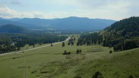 Aerial view of winding road through green valley in Altai Mountains near village Stock Footage 334099811