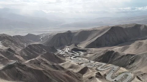 Aerial view of winding road through barren mountains in Xinjiang China Stock Footage 337767575