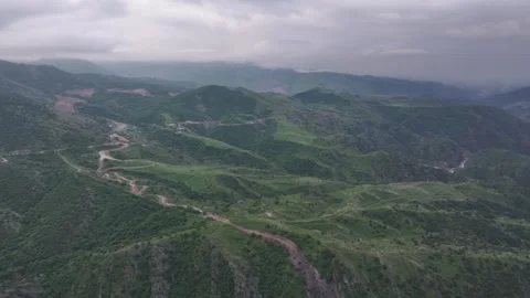 Aerial View of a Winding Road Through Green Hills and a Scattered Town Stock Footage 341891382